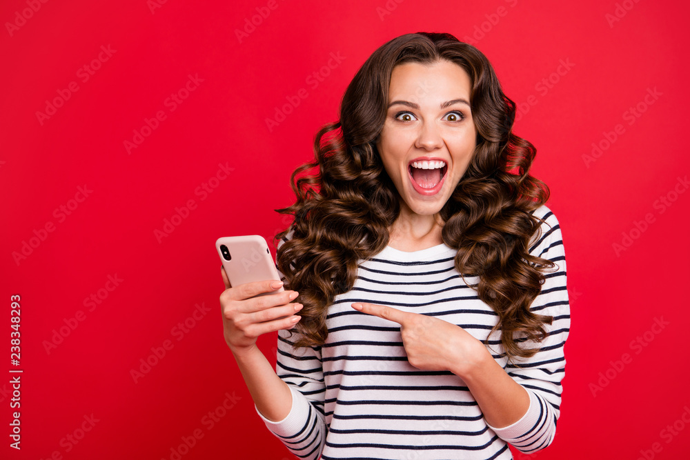 Naklejka premium Portrait of nice lovely crazy funny attractive amazed wondered stunned wavy-haired lady wearing striped pullover pointing at screen sms notification great isolated on bright vivid shine red background