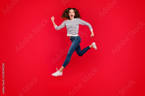 Full length size body photo of fly high pretty charming she her girl going to mall quickly wearing white casual striped sweater denim jeans on red vivid bright background