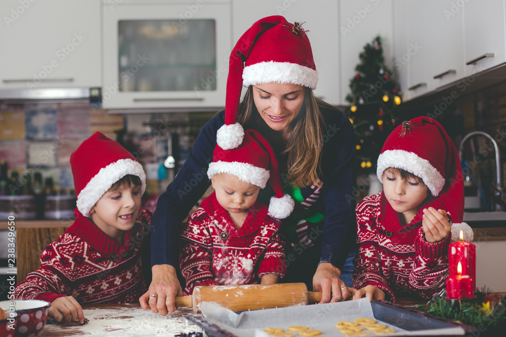 Sweet toddler child and his older brother, boys, helping mommy preparing Christmas cookies at home . Sweet toddler child and his older brother, boys, helping mommy preparing Christmas cookies at home .