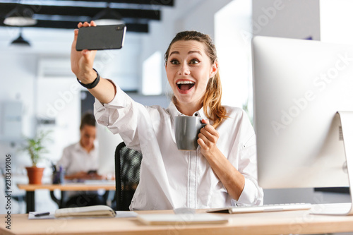 Cheerful young businesswoman sitting at her workplace