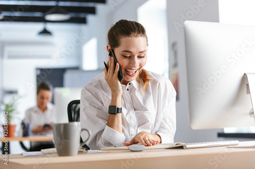 Wallpaper Mural Cheerful young businesswoman sitting at her workplace Torontodigital.ca