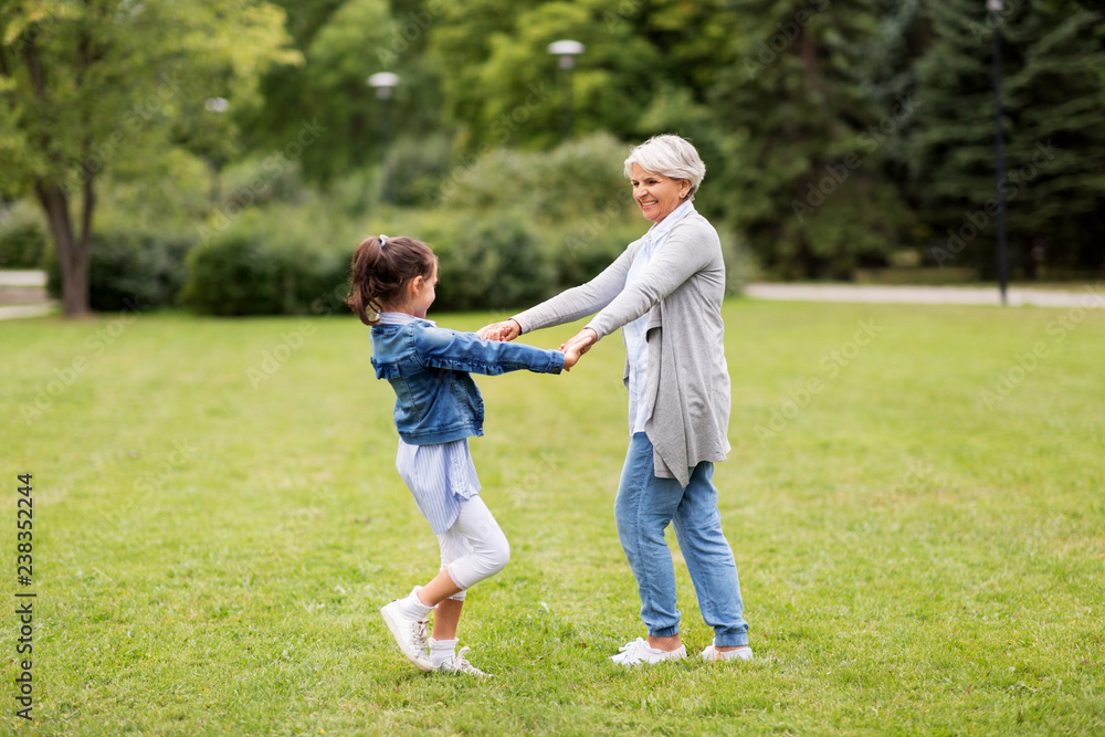 family, leisure and people concept - happy grandmother and granddaughter playing game or dancing at summer park family, leisure and people concept - happy grandmother and granddaughter playing game or dancing at summer park
