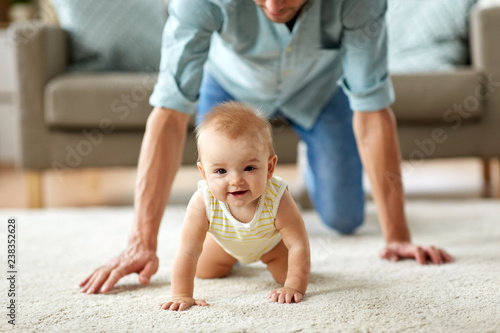 family, fatherhood and parenthood concept - happy little baby girl with father at home crawling on floor photo