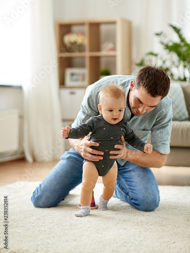 фотографія family, toddling and fatherhood concept - father helping little baby daughter wi