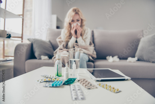 Close-up view of pile medicine colorful pills c-vitamin health support blonde girl suffering from allergy sitting on divan in light room