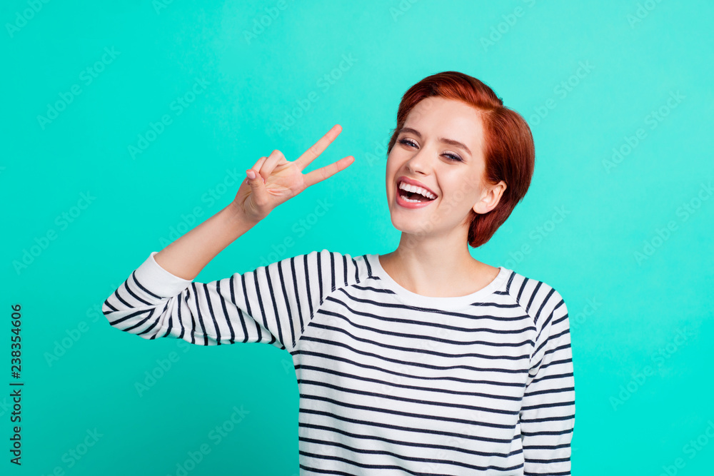 Portrait of nice charming pretty winsome attractive cheerful glad red-haired lady in striped pullover showing v-sign isolated over bright vivid shine green turquoise background Portrait of nice charming pretty winsome attractive cheerful glad red-haired lady in striped pullover showing v-sign isolated over bright vivid shine green turquoise background