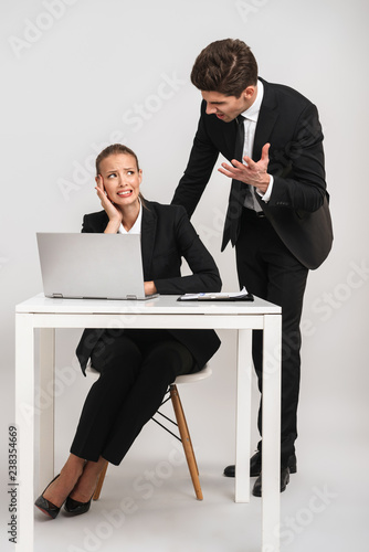 Upset business couple wearing suits isolated