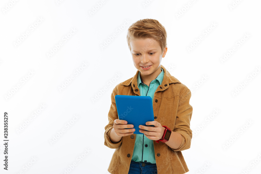 Happy positive young boy holding his tablet Happy positive young boy holding his tablet