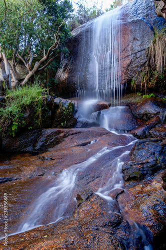 Waterfall into stream over flat rocks