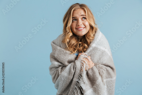 Image of gorgeous woman 20s wrapped in blanket looking at camera, isolated over blue background photo