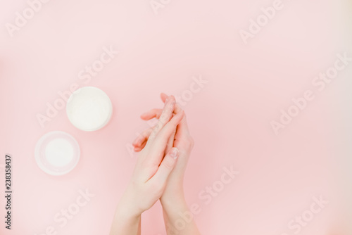 Female hands with a box of hand cream. Hand skin care concept. Pink abstract background. Top view horizontal several objects.