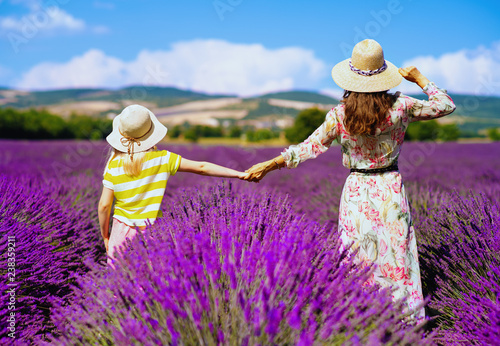 mother and daughter against lavender field stand holding hands