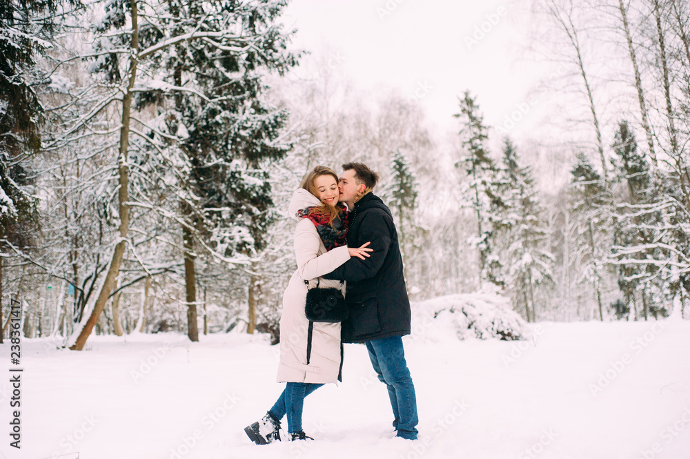 Young couple hugging and kissing in the forest in winter. Young couple hugging and kissing in the forest in winter.