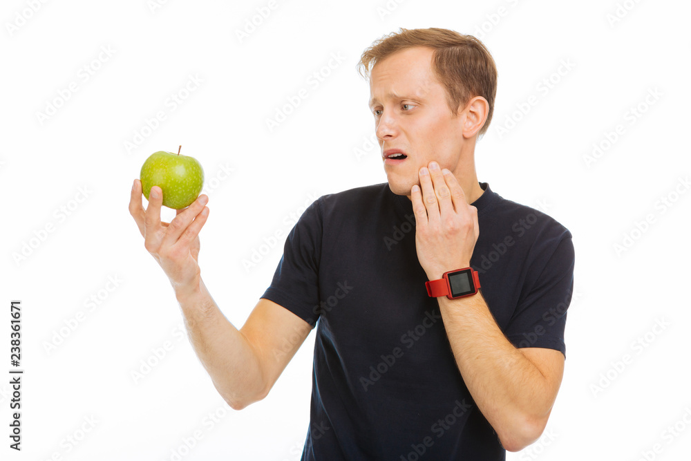 Sad cheerless man looking at the green apple Sad cheerless man looking at the green apple