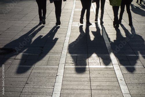 Silhouettes and shadows of people walking along a city street. Contrast of light and shadow
