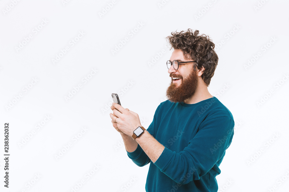 Portrait of cheerful bearded hipster man using smartphone over white background Portrait of cheerful bearded hipster man using smartphone over white background