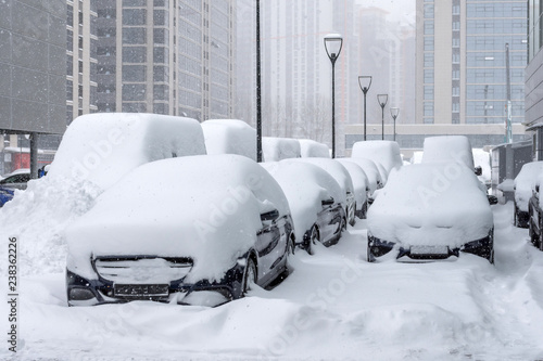 Many cars parked in the business district of the city during a snow storm photo