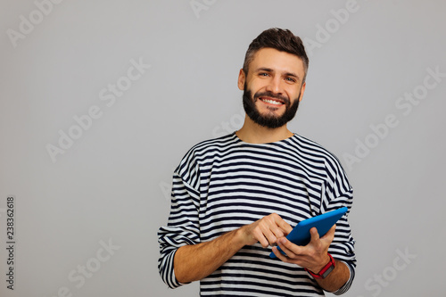 Delighted bearded young man using latest gadgets
