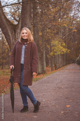 Girl in coat with umbrella in the park.