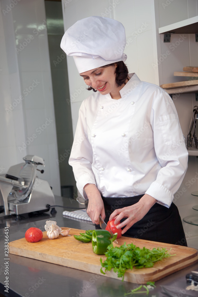 A smiling white woman cook preparing salad in a restaurant in the kitchen. Vertical frame A smiling white woman cook preparing salad in a restaurant in the kitchen. Vertical frame