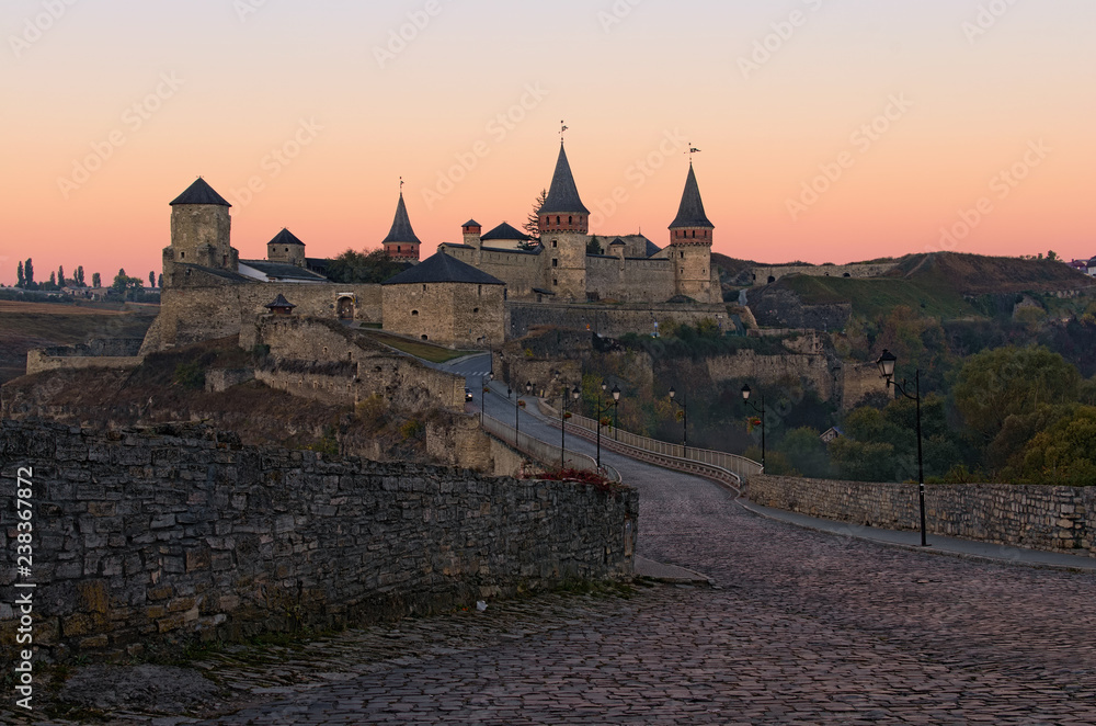 Picturesque view of medieval Kamianets-Podilskyi castle during autumn sunrise. Famous touristic place and romantic travel destination. Kamianets-Podilskyi, Khmelnitsky region, Ukraine