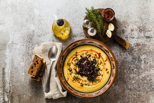 Authentic Greek Fava recipe, Middle Eastern yellow lentil soup with caramelized onions, paprika and capers. vegan healthy food in clay pots on the stone table