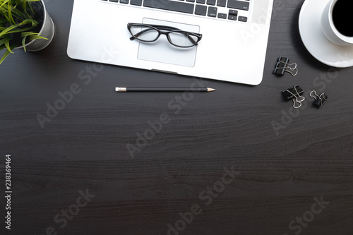 Flat lay of top view modern black wood desk work table with computer laptop and stationary in home office includes copyspace for add text or graphic