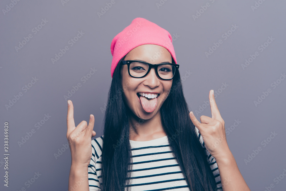Close-up portrait of nice cool lovely attractive cheerful cheery childish optimistic positive straight-haired girl wearing striped pullover showing double horns isolated on grey gray pastel background Close-up portrait of nice cool lovely attractive cheerful cheery childish optimistic positive straight-haired girl wearing striped pullover showing double horns isolated on grey gray pastel background