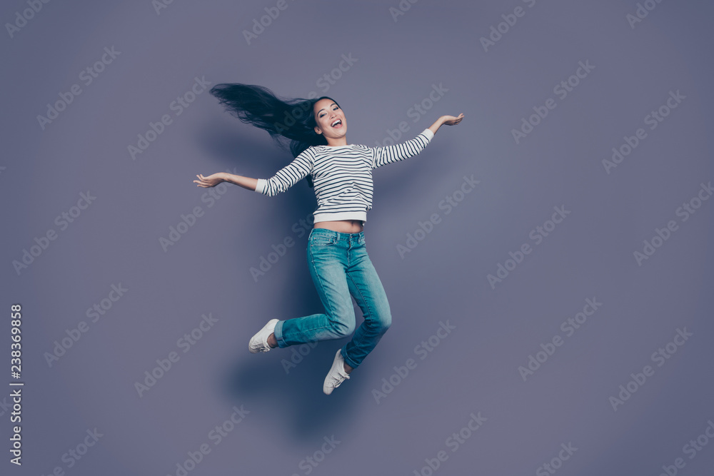 Full length body size view of lovely attractive cheerful positive optimistic girl wearing striped pullover jeans denim having fun rejoicing in air isolated over violet purple pastel background