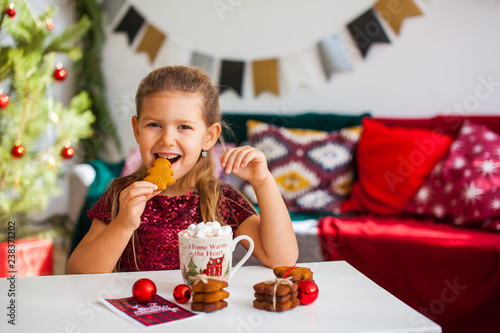 Wallpaper Mural Little girl in red dress eating Christmas cookies with cacao in cup, red Chirstmas decorations around Torontodigital.ca