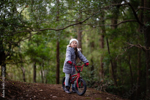 Fototapeta Naklejka Na Ścianę i Meble -  森の中で自転車に乗る女の子