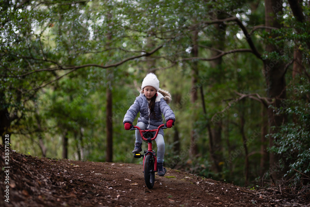 Obraz premium 森の中で自転車に乗る女の子