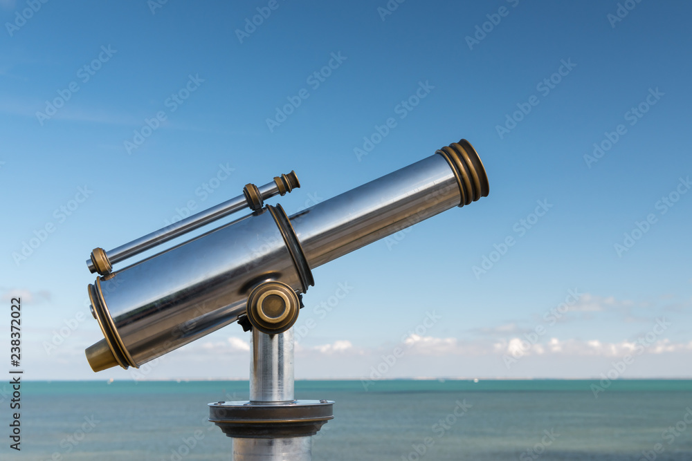 Shiny metallic telescope in front of the sea Shiny metallic telescope in front of the sea