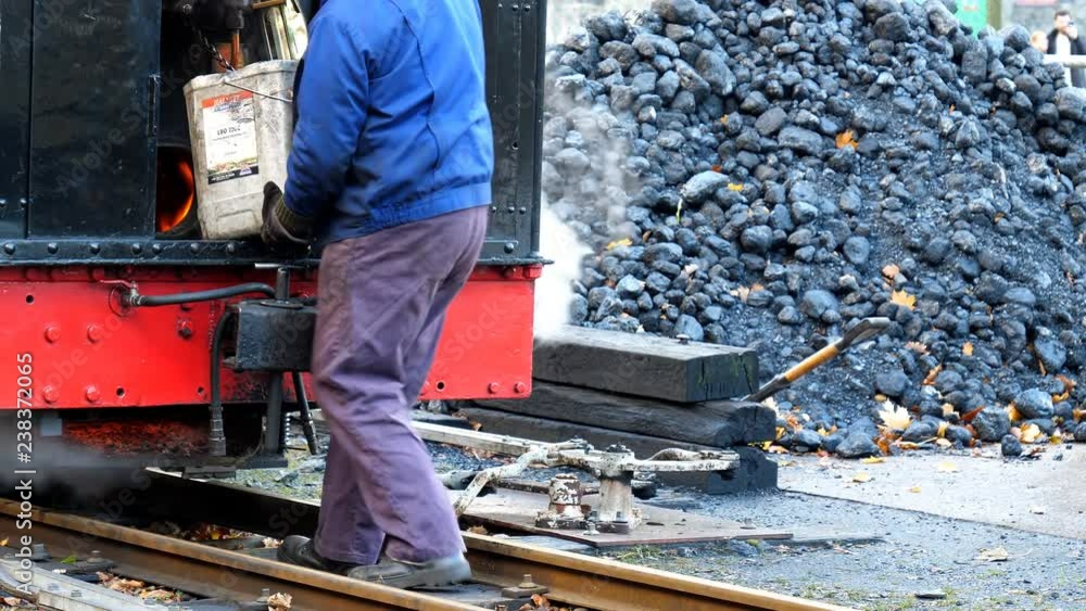 Unrecognizable man in workwear bringing bucket of coal for a steam engine Unrecognizable man in workwear bringing bucket of coal for a steam engine
