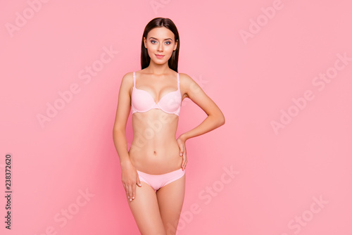 Close up portrait of gorgeous tender gentle skinny cute her she girl standing showing nice tight body touching hip and side wearing pale pink underwear isolated on pink background © deagreez