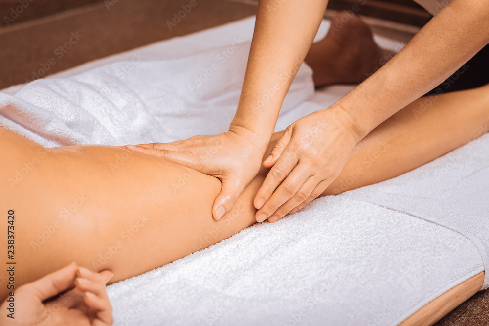 Professional female masseuse touching her clients leg Professional female masseuse touching her clients leg
