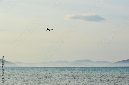 the plane against the backdrop of a clean blue sky flies on the sea and majestic mountains