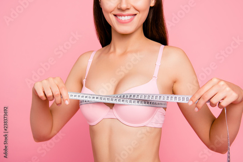 Cropped close-up photo of nice cute adorable attractive cheerful positive optimistic girl in beige bra measuring chest size line with tape isolated over pink background