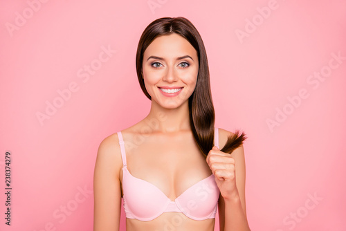 Close-up portrait of nice cute lovely charming attractive positive girl in beige bra holding in hand healthy shine strong straight hair curls ends isolated over pink pastel background