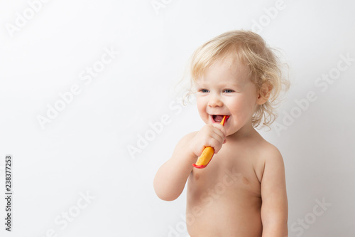 little cute curly baby smiles and cleans teeth on white background