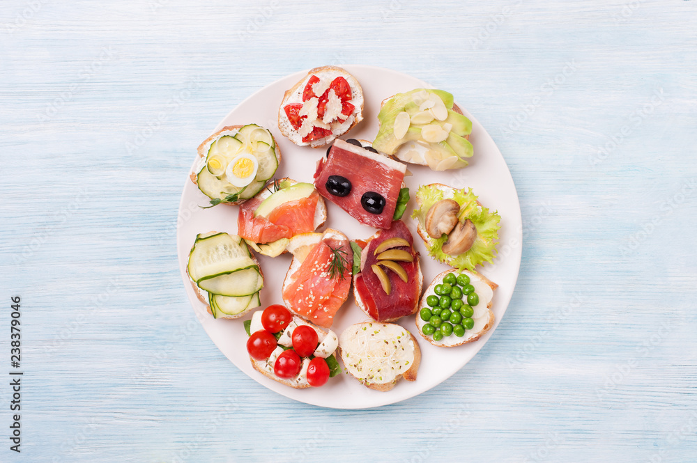 Different kinds canapes in plate on the wooden background. Different kinds canapes in plate on the wooden background.