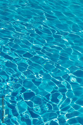 Blue water in swimming pool background. Ripple Water in swimming pool with sun reflection. Blue swimming pool rippled water detail. vertical photo © jollier_