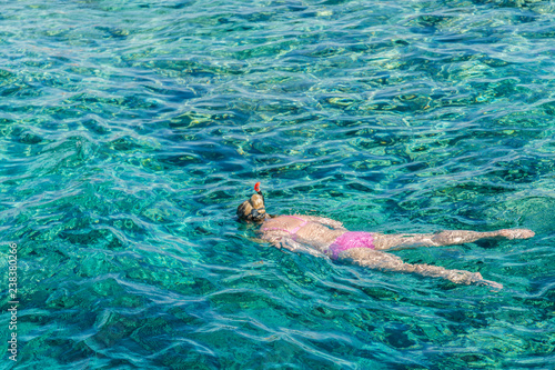 Young girl snorkeling in tropical water on vacation. Woman swimming in blue sea. Snorkeling girl in full-face snorkeling mask.