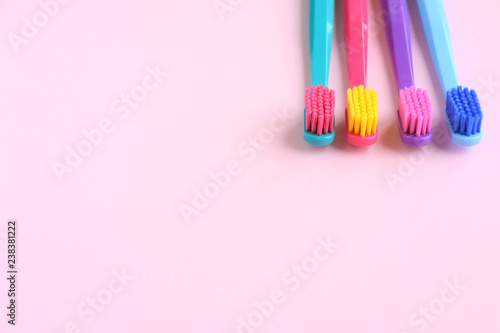 Colorful bright toothbrushes with selective focus on pink background. Toothbrush for personal morning hygiene on neutral blurred backdrop. Dental plastic tool with empty space for image or text