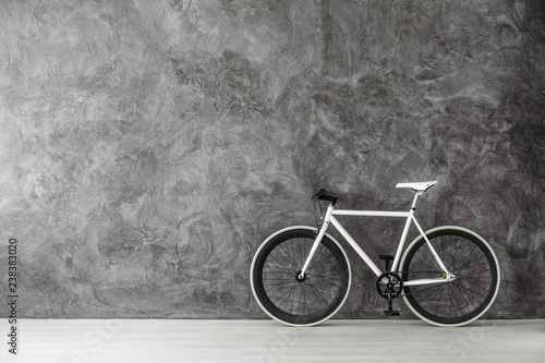 White bike on grey concrete wall, real photo with copy space