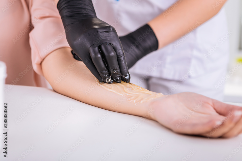 Blonde-haired master in hair removal smiling while working