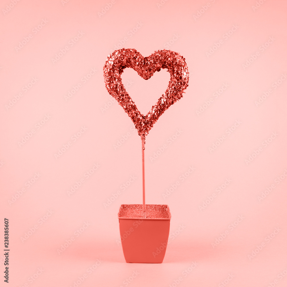 Glitter heart in flower pot on pink background. Valentines day and love growth concept . Living coral theme - color of the year 2019 Glitter heart in flower pot on pink background. Valentines day and love growth concept . Living coral theme - color of the year 2019