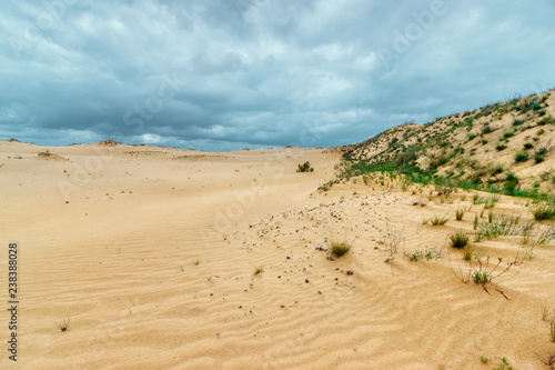 The sandy desert with hills covered with poor grass vegetation. Stormy cloudy sky. Forthcoming raining in the waterless land. Rostov-on-don region, Russia