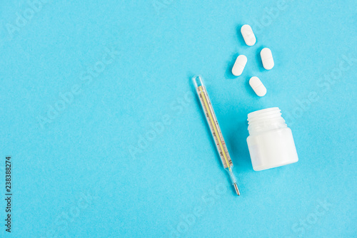 Pills and thermometer on a blue background