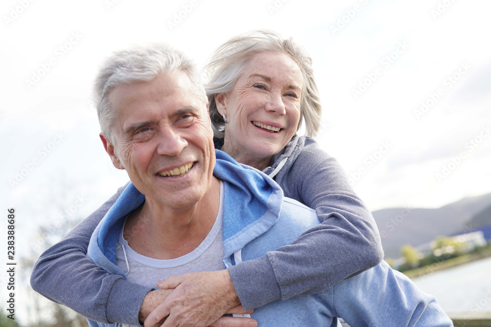  Fun loving senior couple piggyback riding outdoors